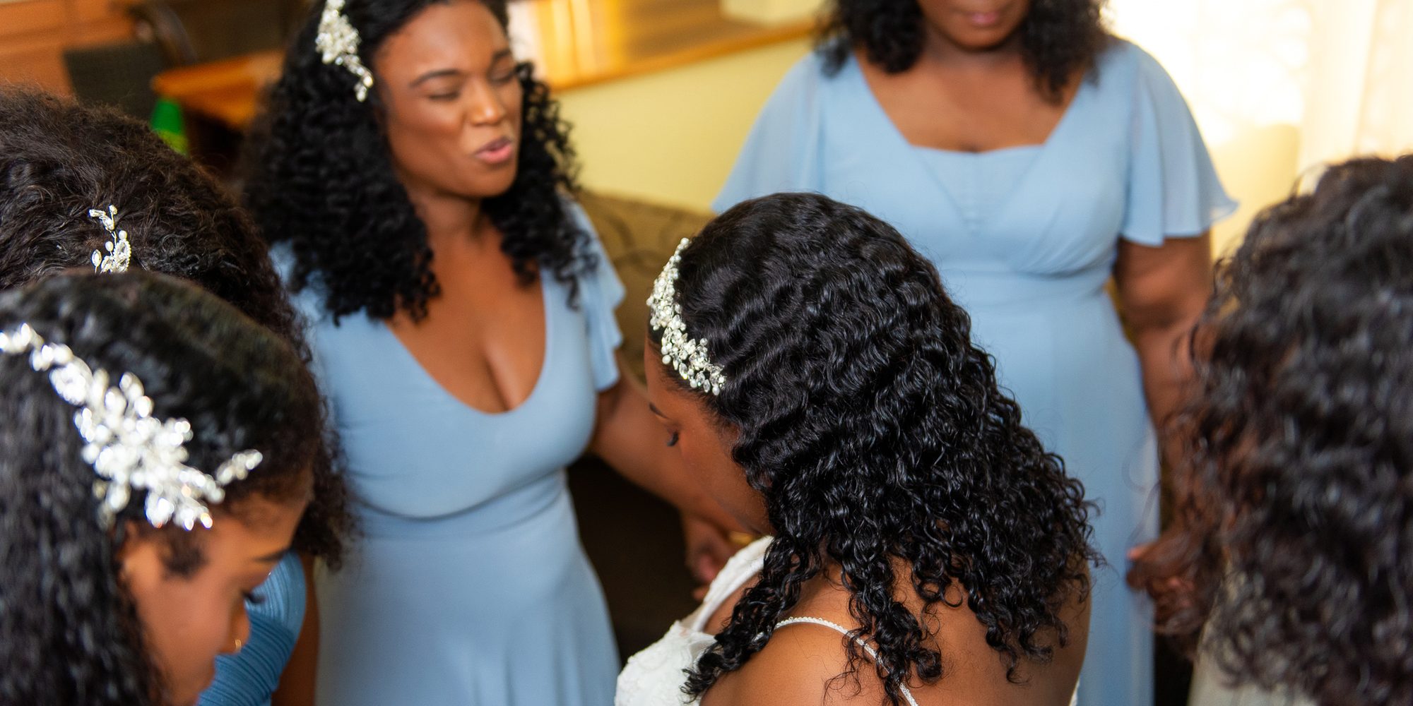 Bridesmaids gathered around the bride with heads bowed before the ceremony