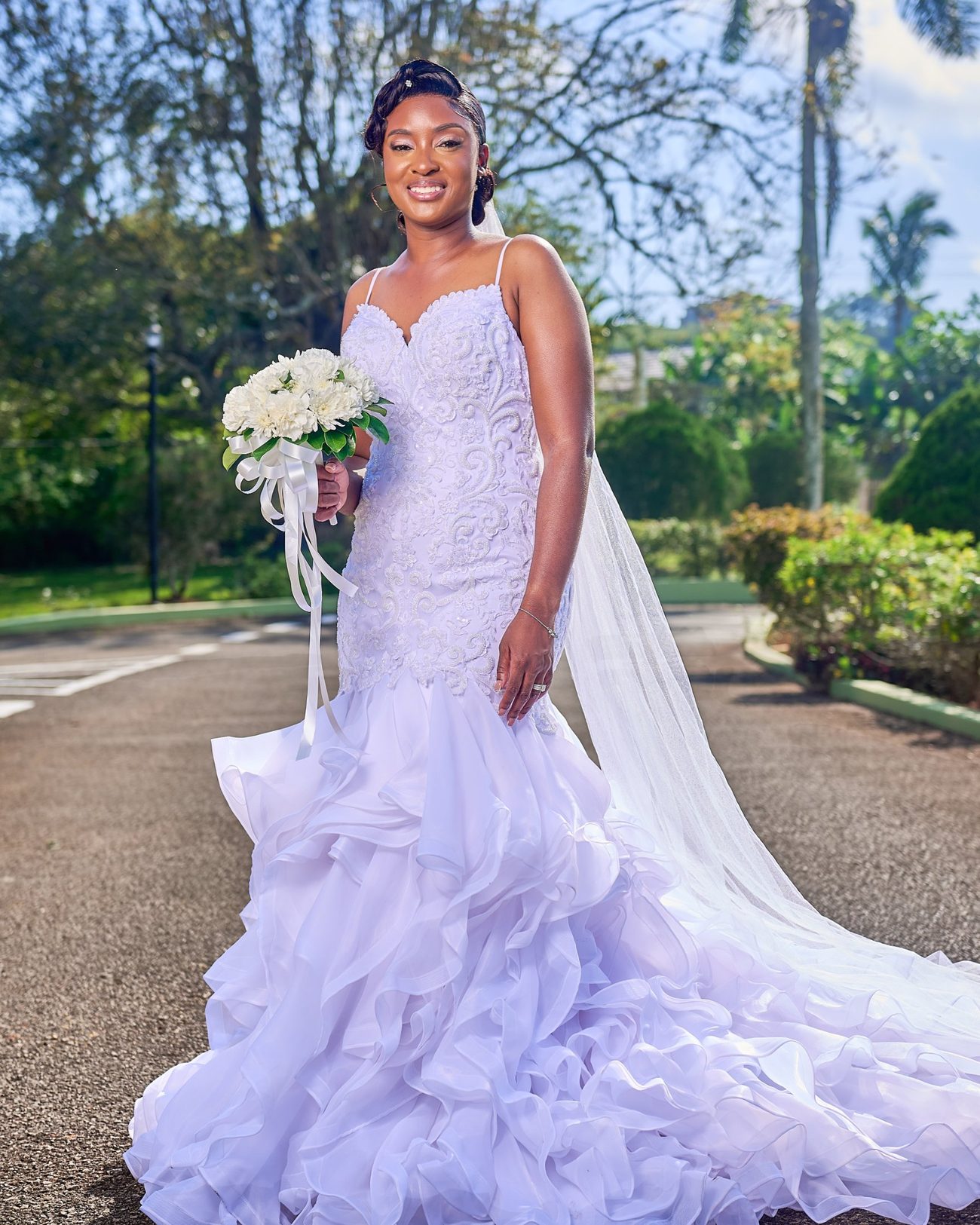 A bride in a ruffled gown with a long veil trailing behind her