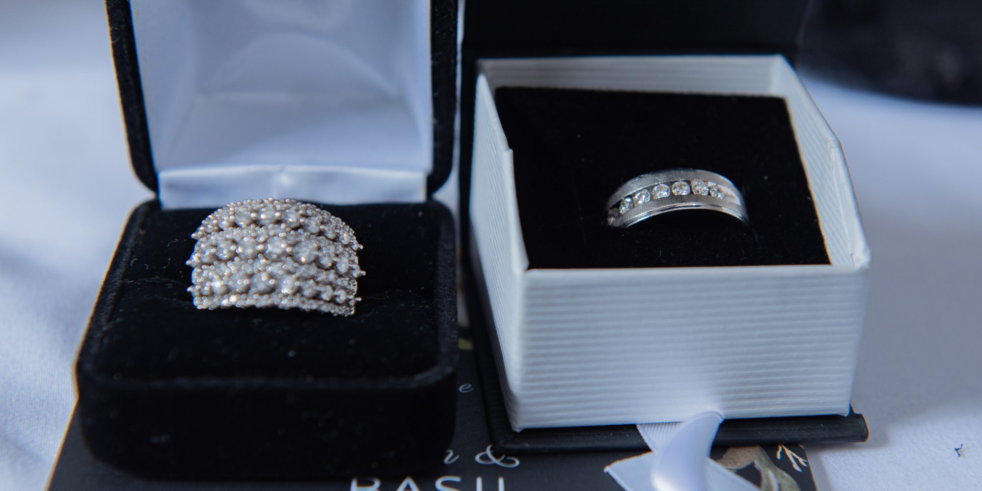 Two wedding rings in their boxes, resting on the order of service